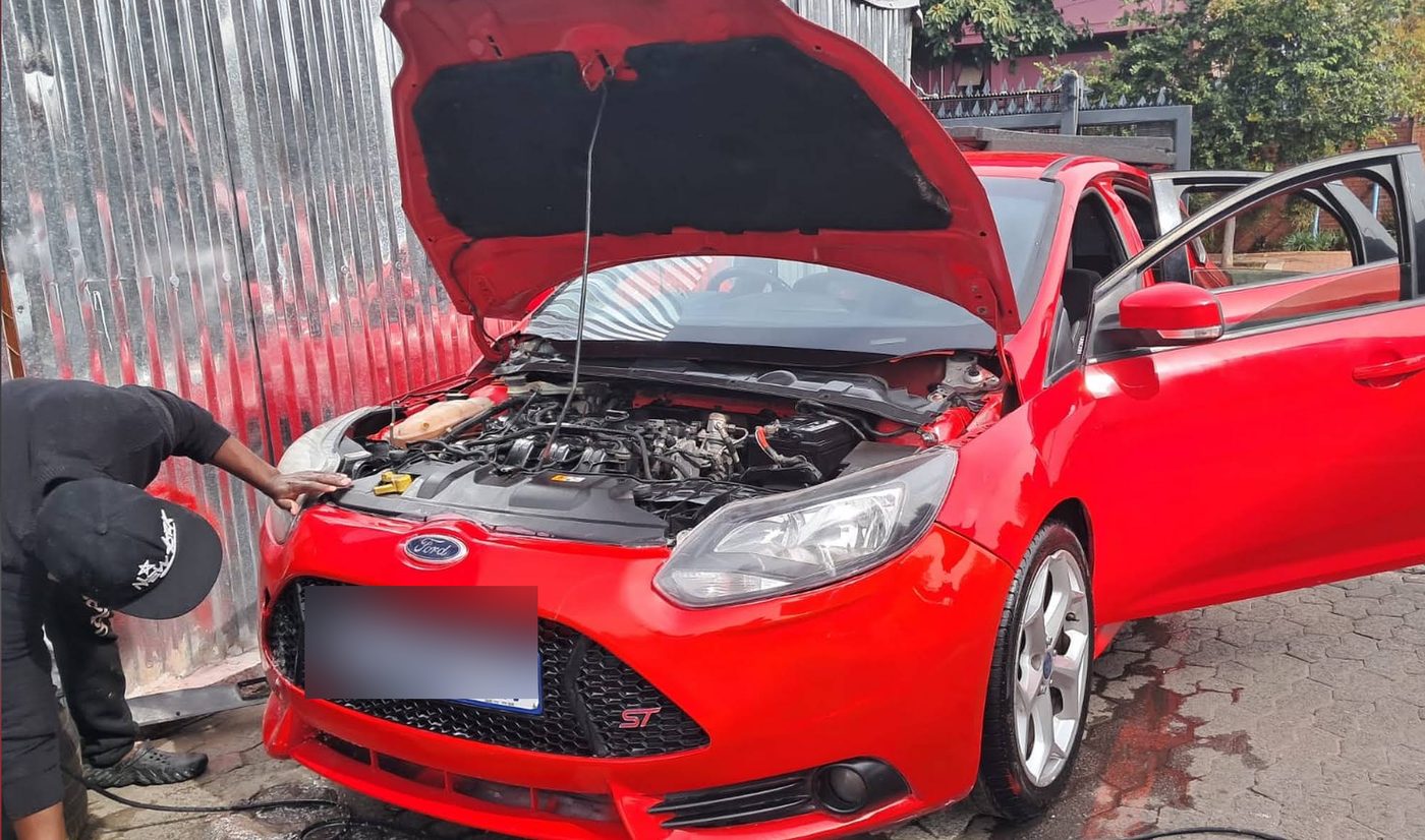 Mechanic checking the engine bay of a red Ford Focus ST