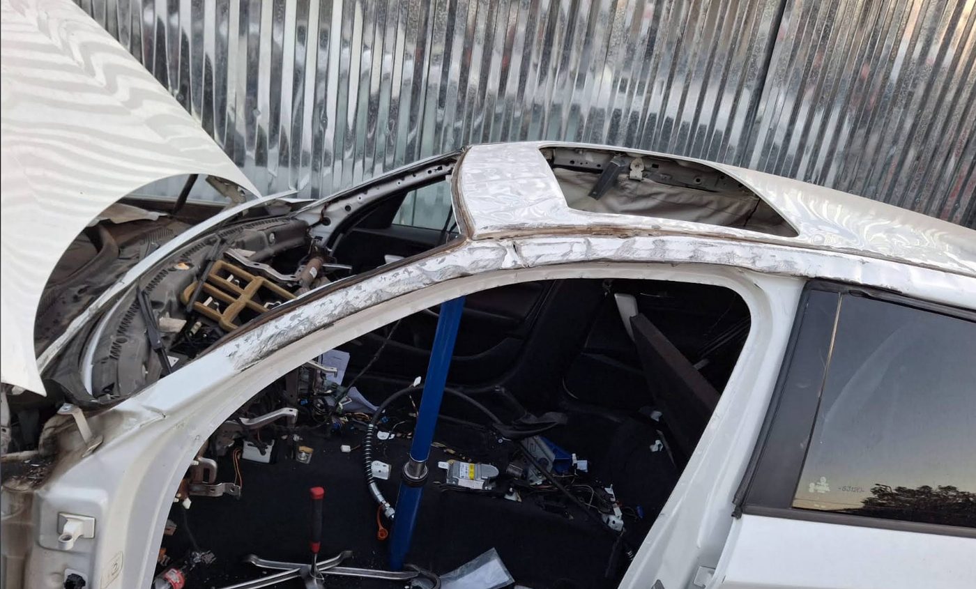 White car stripped down for roof and pillar repairs after an accident